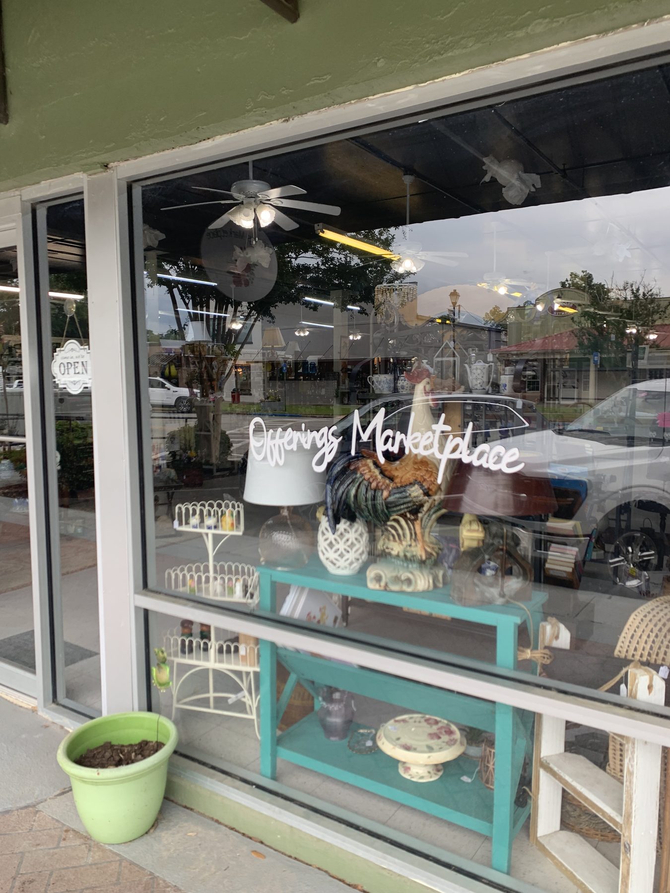 Offerings Marketplace shop window filled with antique lamps, pottery, and collectibles on a teal display table